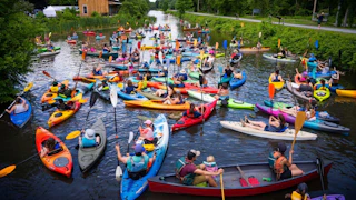 A group of kayakers participating in the annual Boat Float N Folk Festival